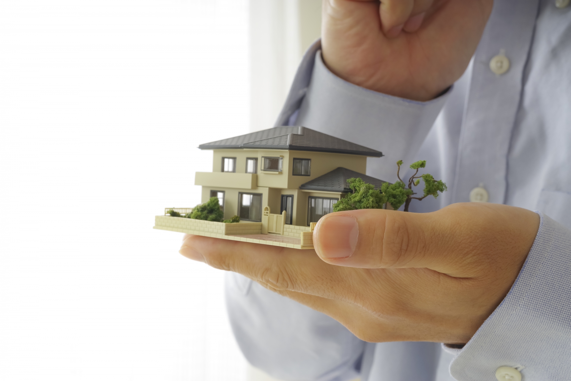 住宅模型を手に考え事をしている男性