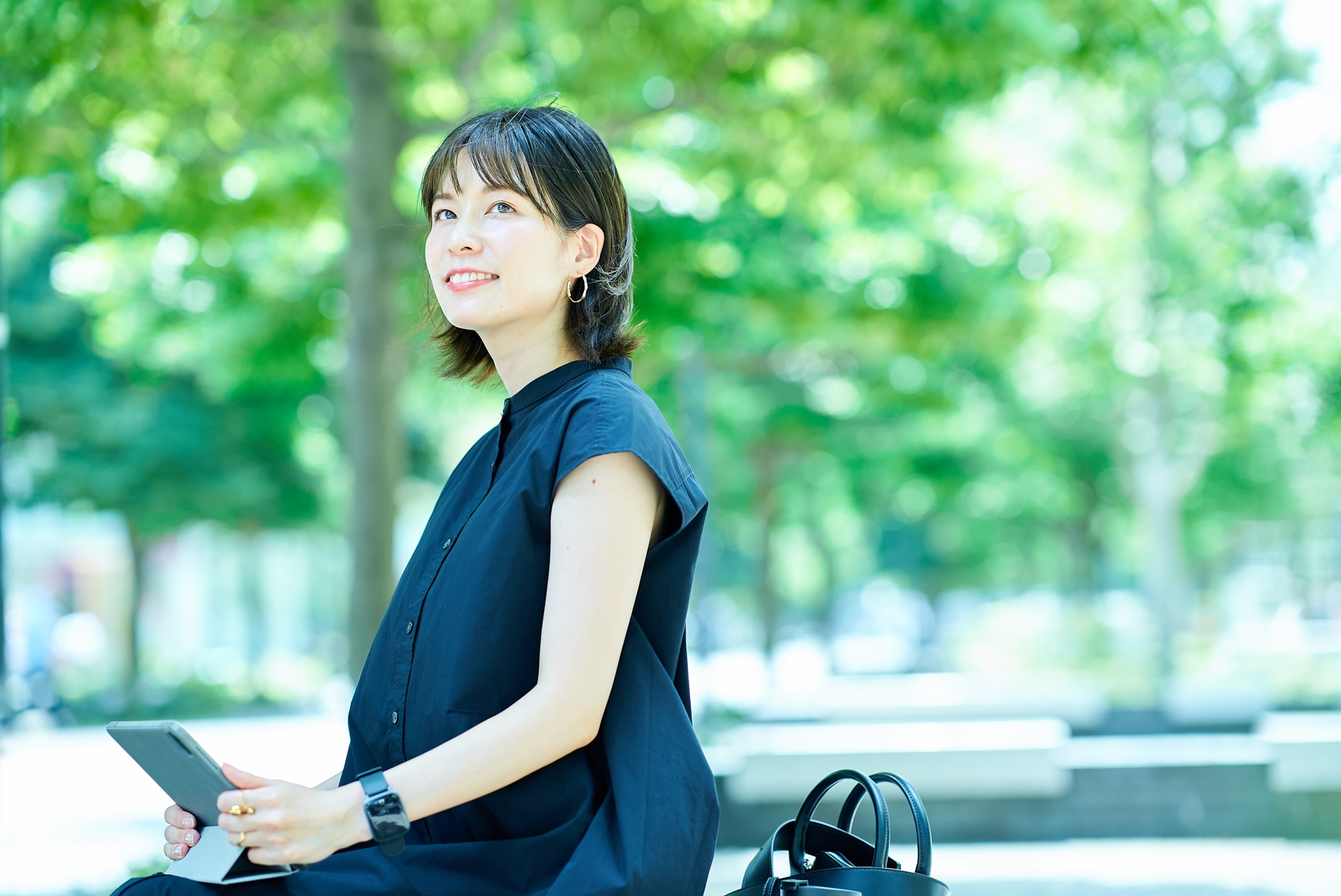 屋外でタブレットPCを操作する若い女性