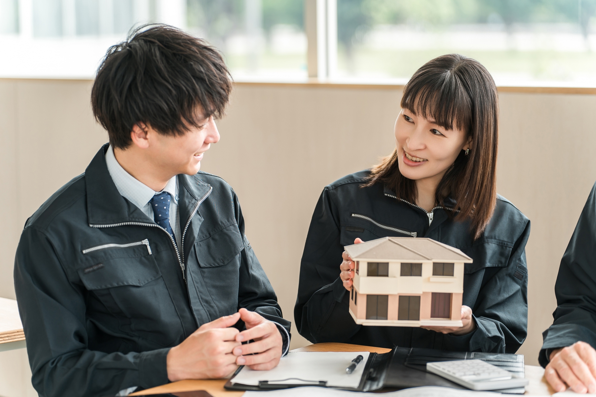 住宅模型を持つ住宅メーカーの男女