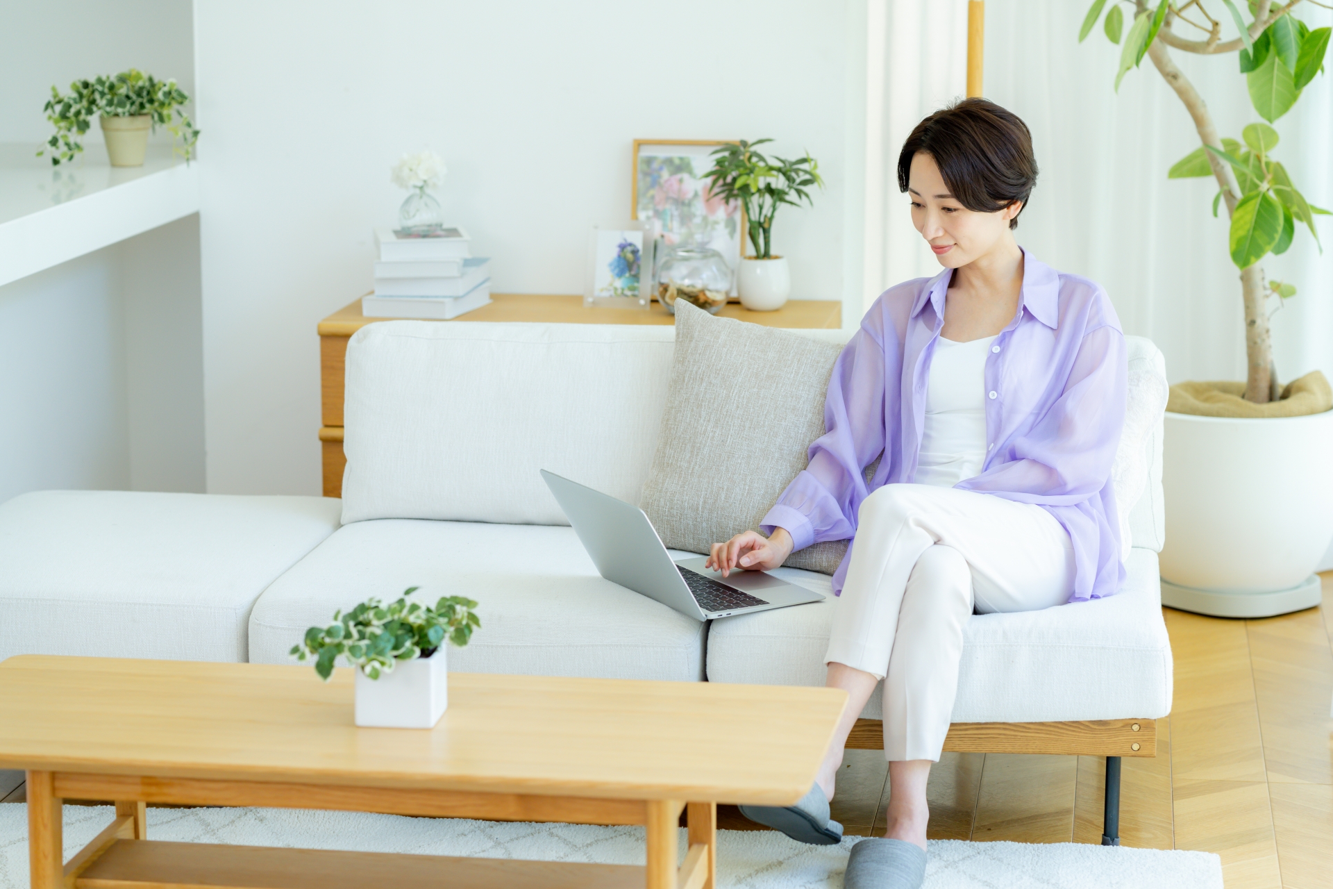部屋でノートパソコンを使うミドル女性