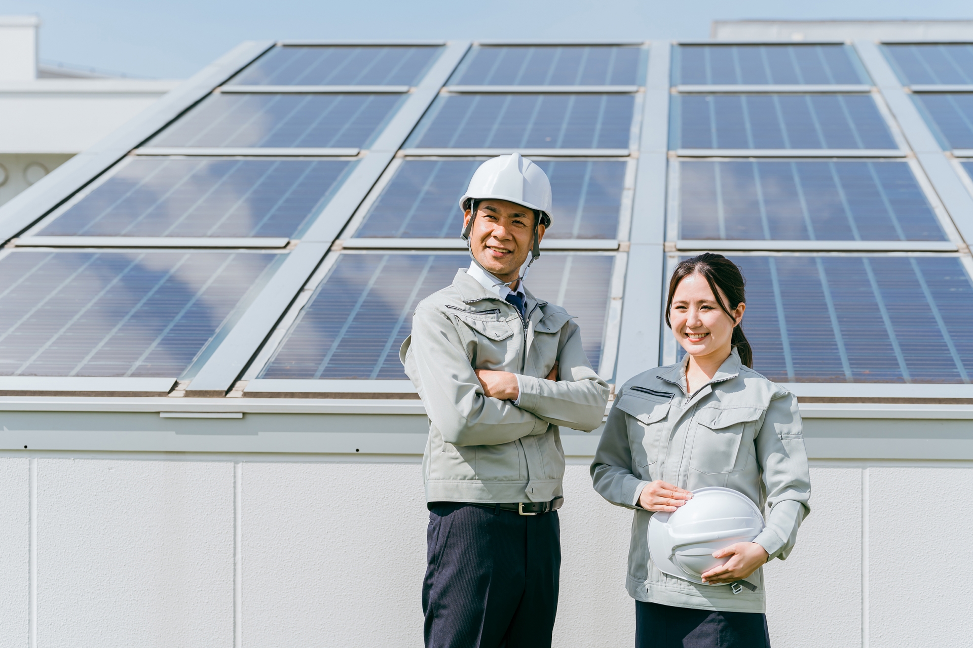 ソーラーパネルの前に立つ電力会社の技術者