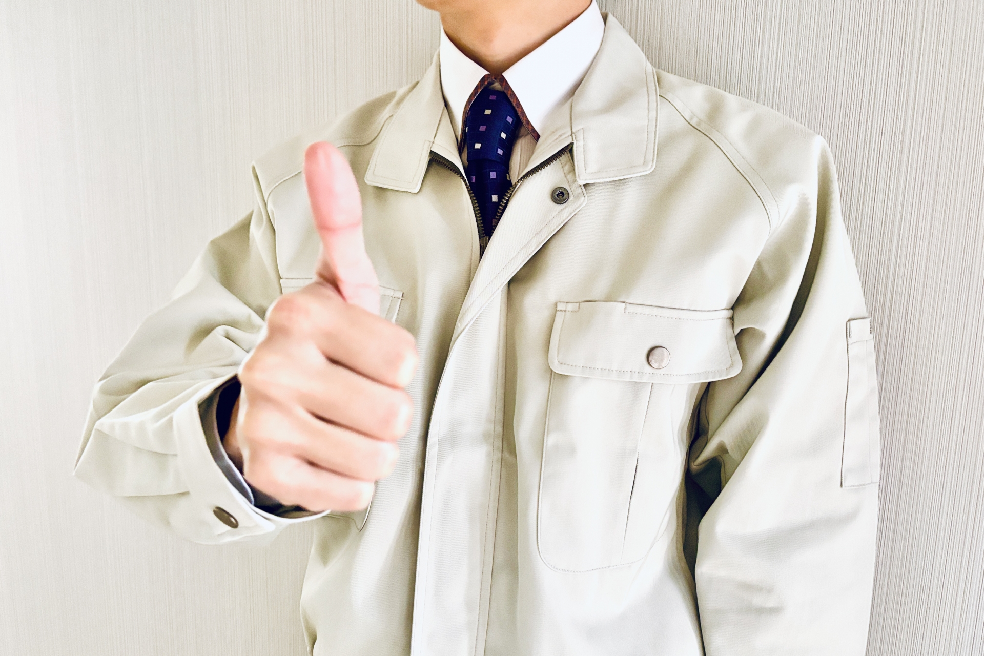 親指を立てる作業着姿の男性
