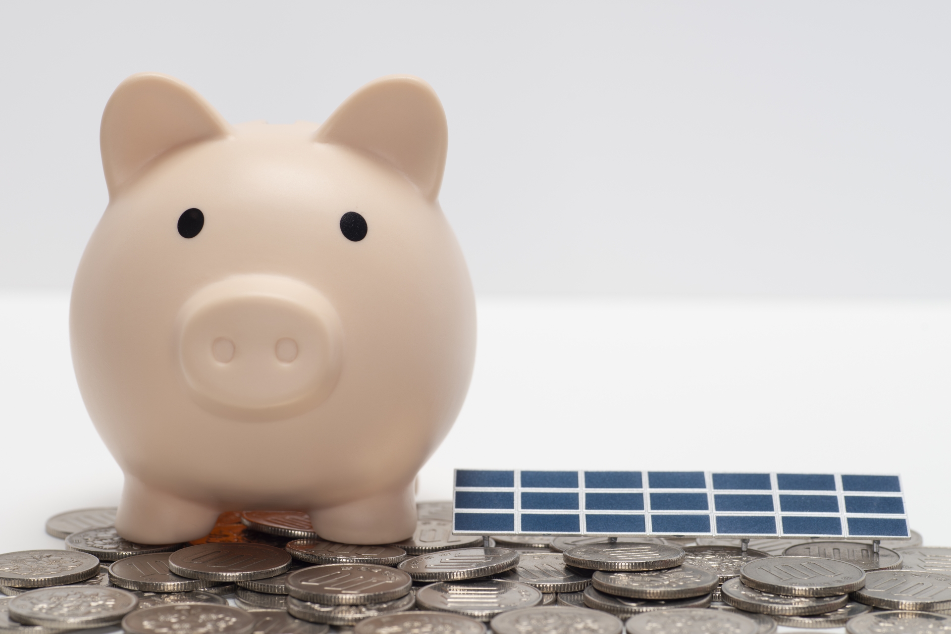 太陽光パネルのミニチュアと貯金箱とコイン