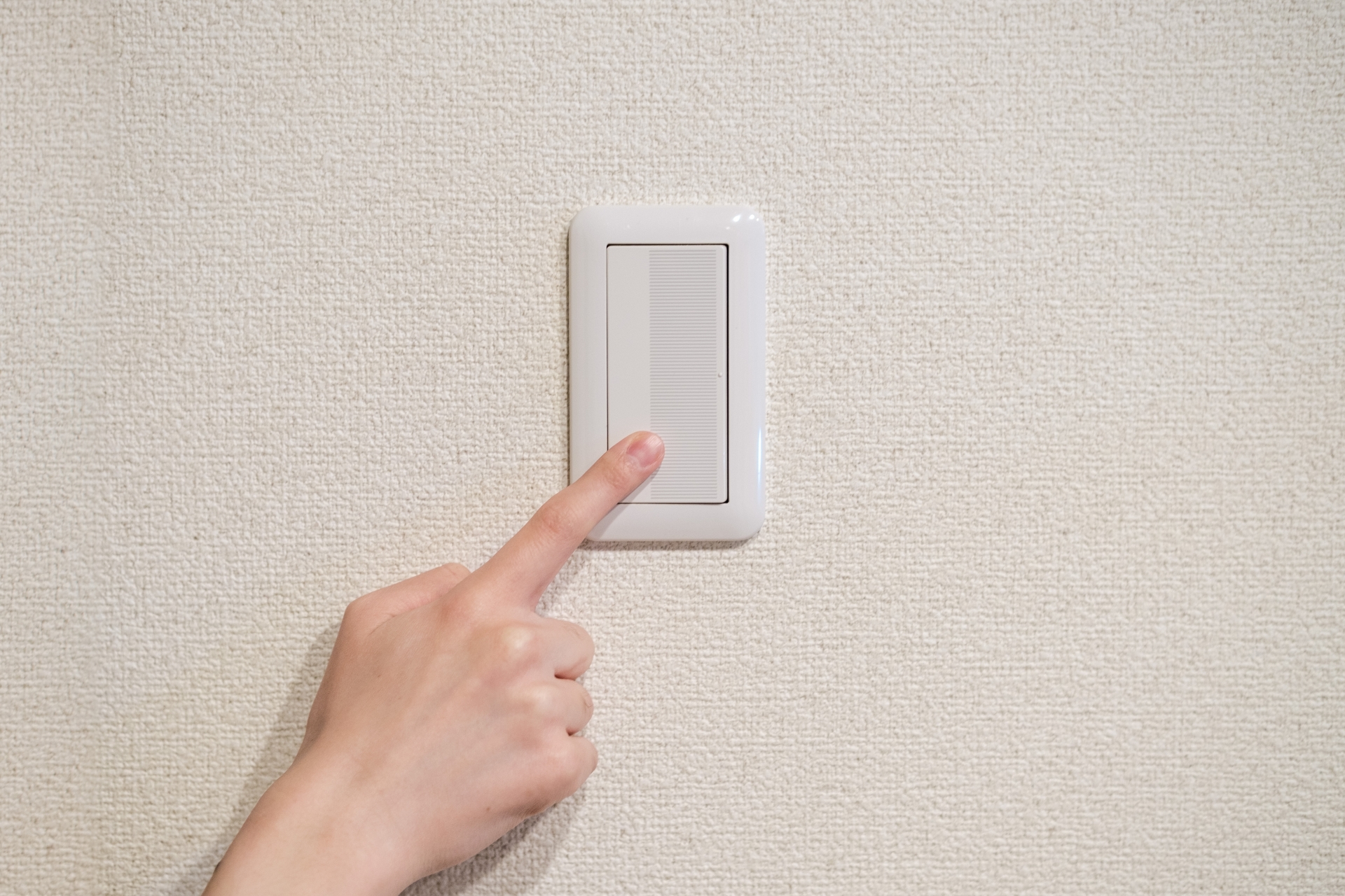 部屋の電気のスイッチを押している人の手