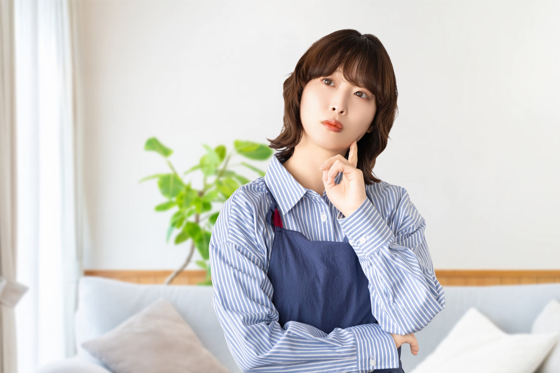 考えごとをするエプロン姿の女性