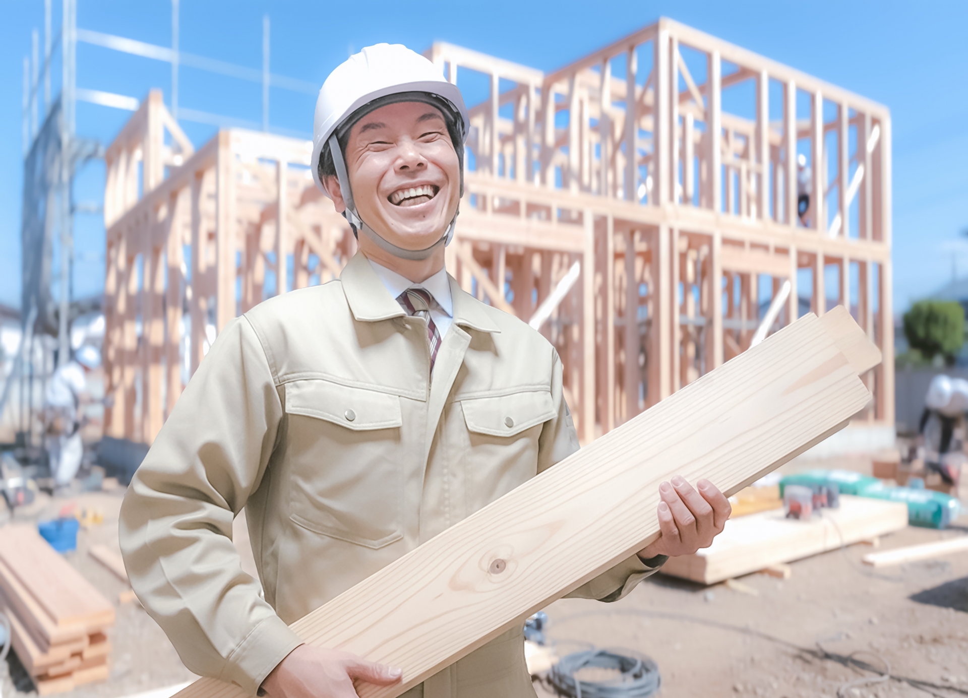 木材を持ち笑顔を見せる作業服の男性