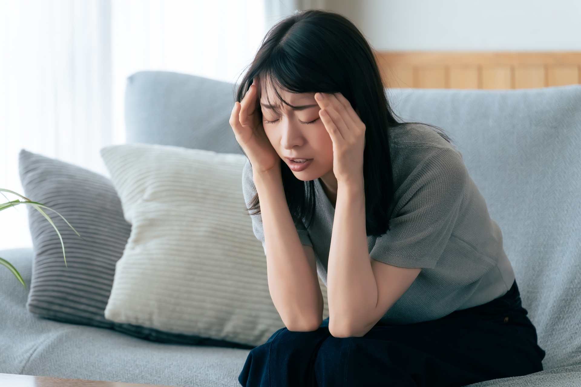 頭を押さえて悩む女性