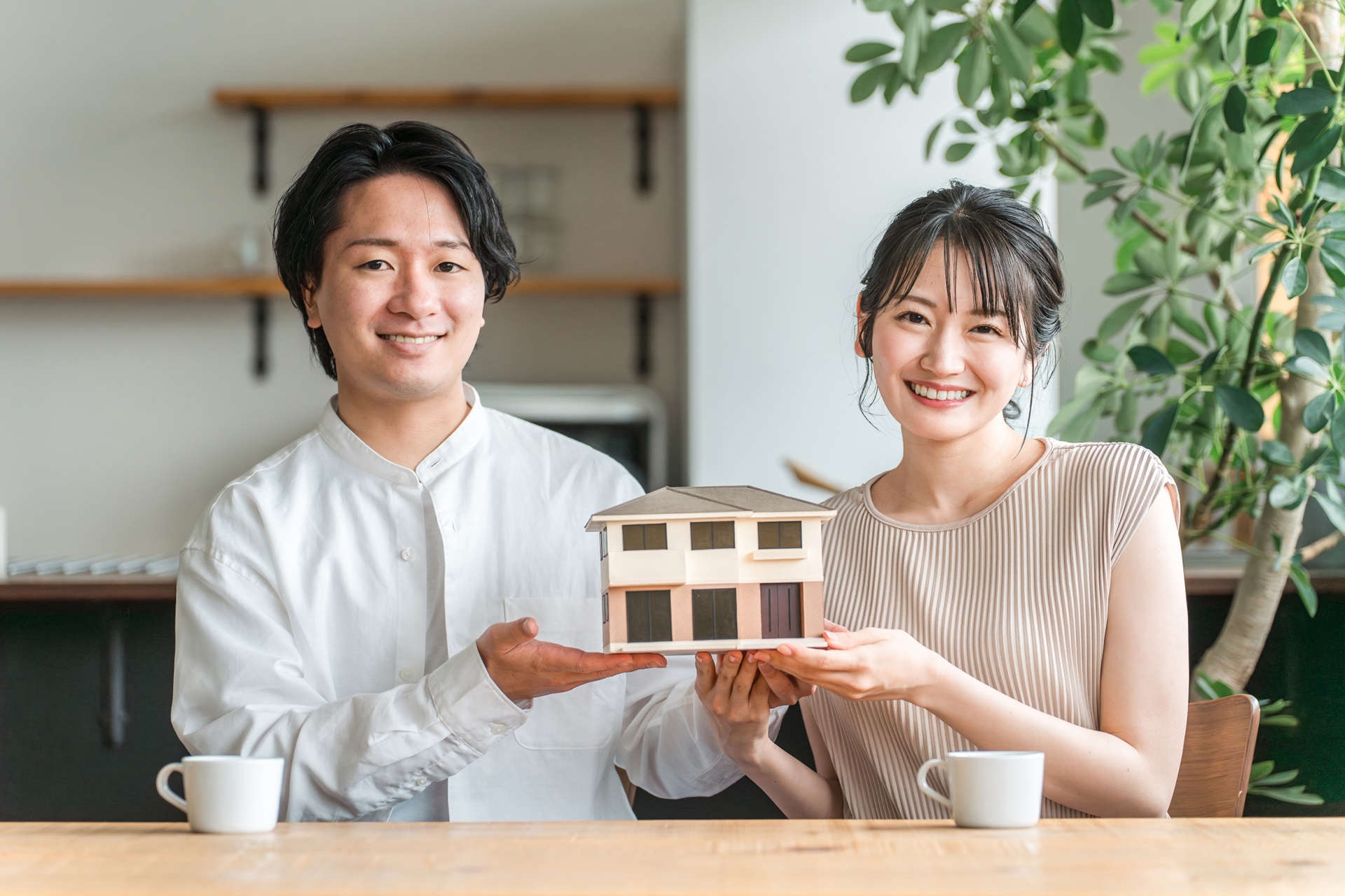 住宅模型を持つ若い夫婦（マイホーム）