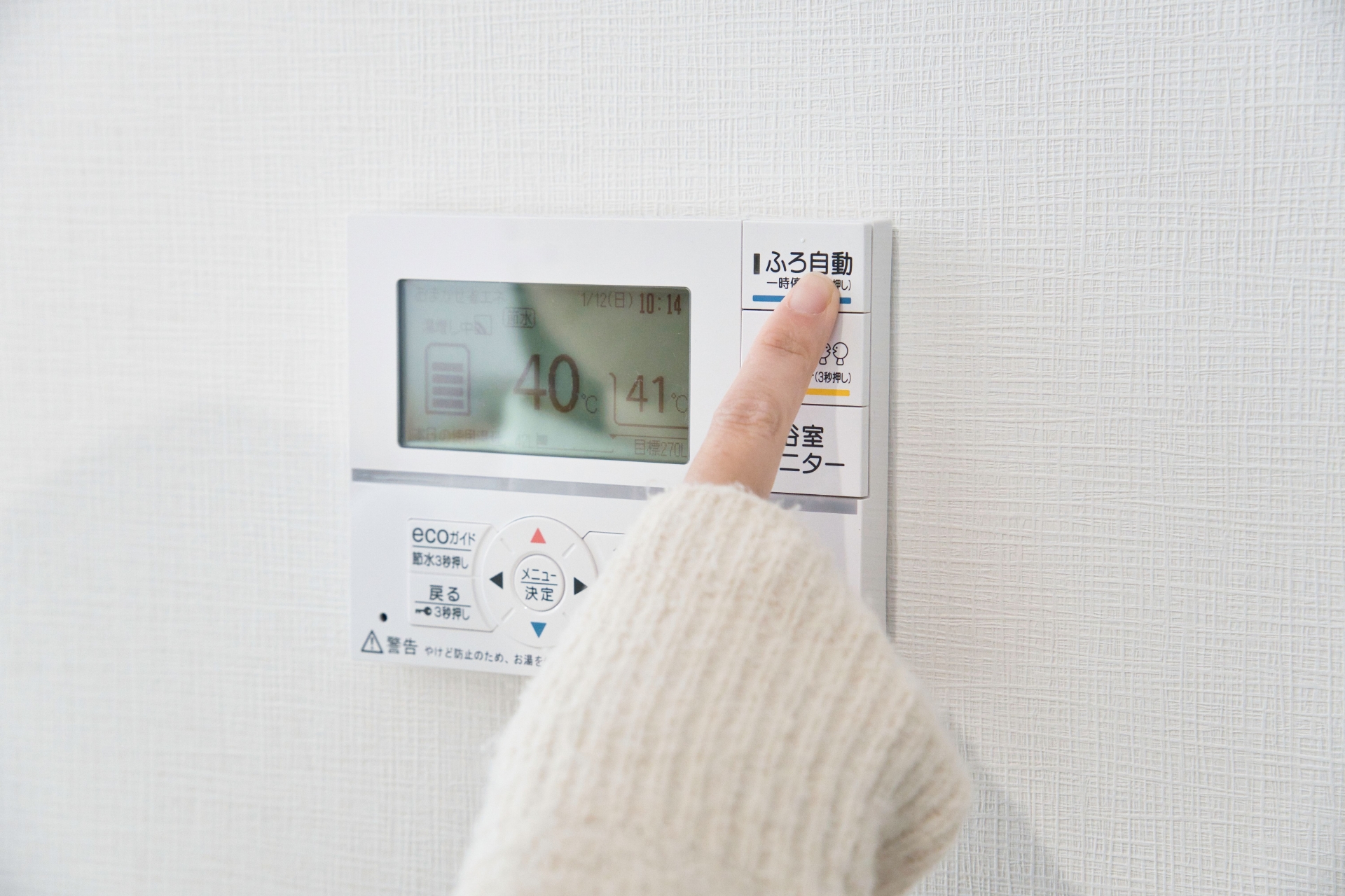 給湯機を操作してお風呂にお湯をはる女性