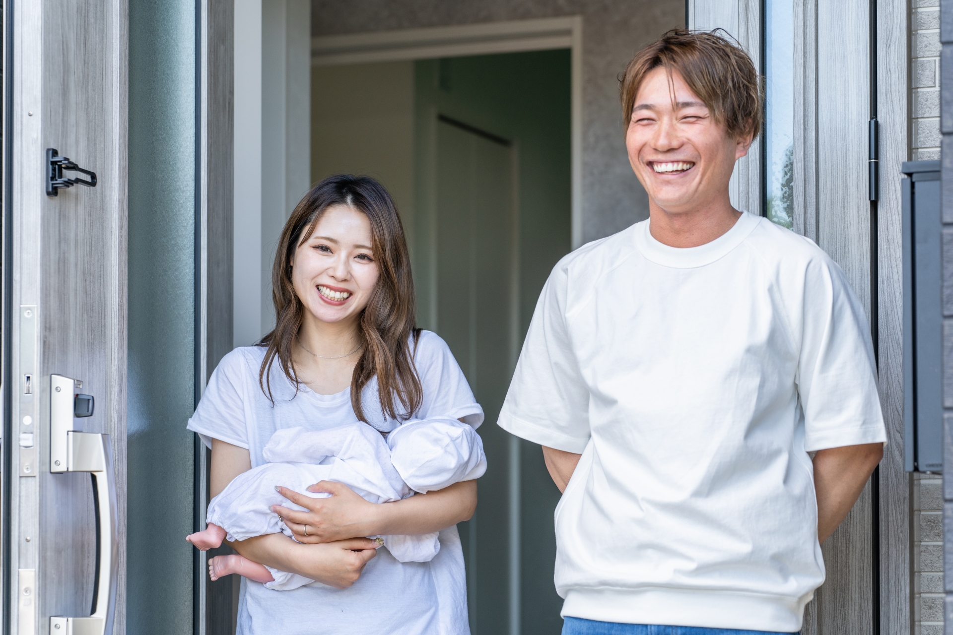 玄関で出迎える赤ちゃんを抱っこする夫婦