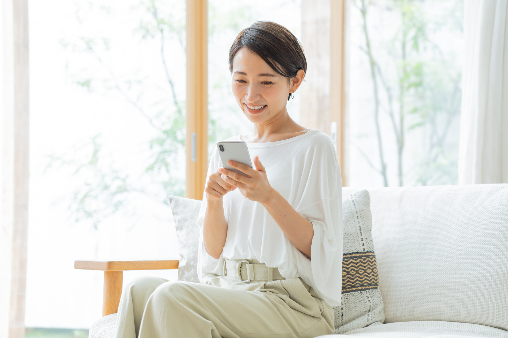 ソファに座り携帯を持つ日本人女性