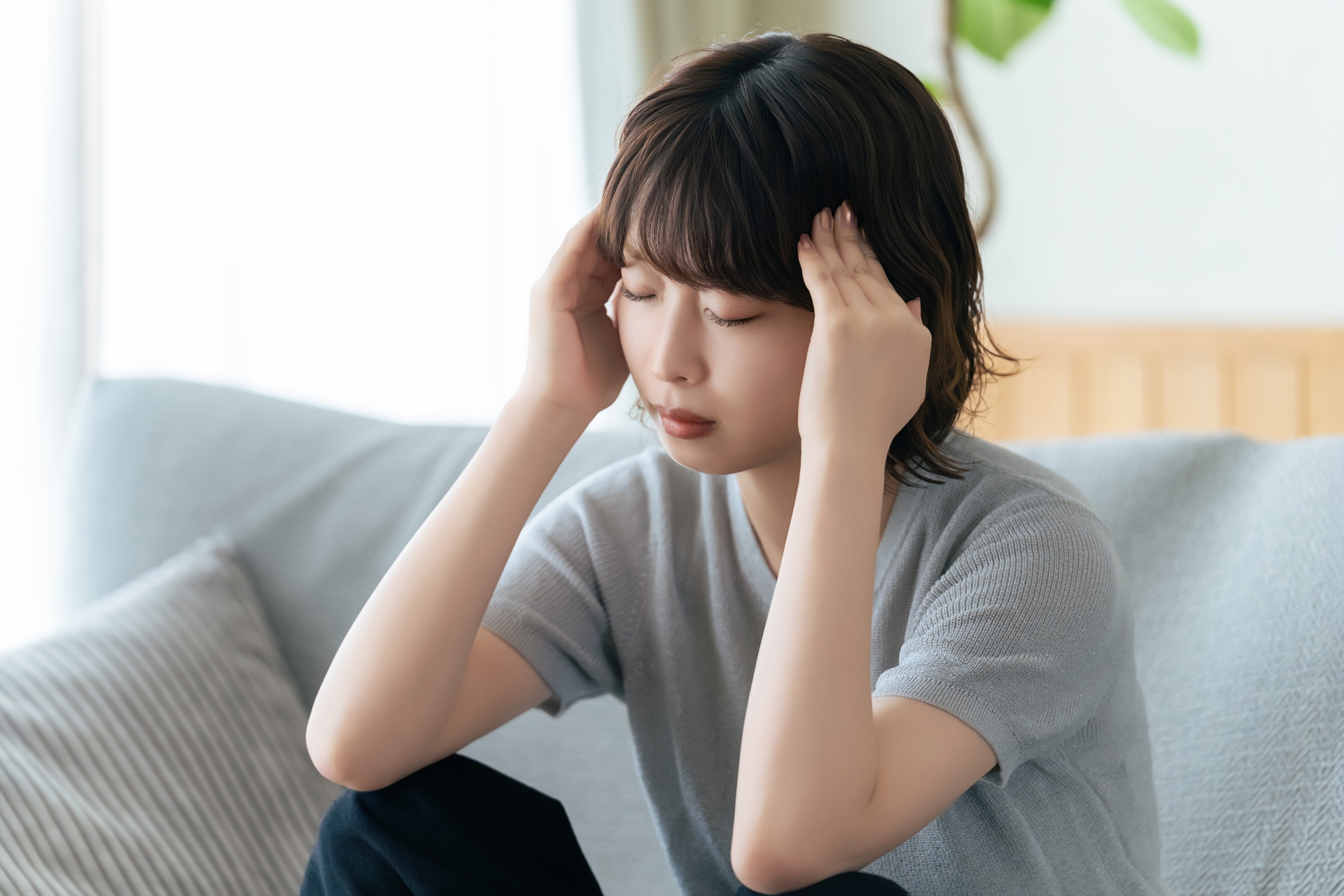 頭を押さえて悩む女性