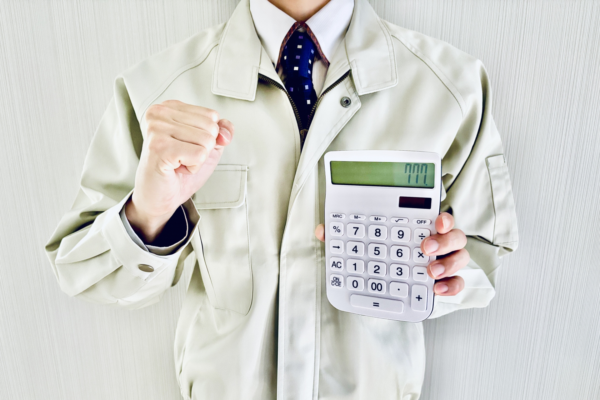 電卓を持ってガッツポーズする作業着の男性