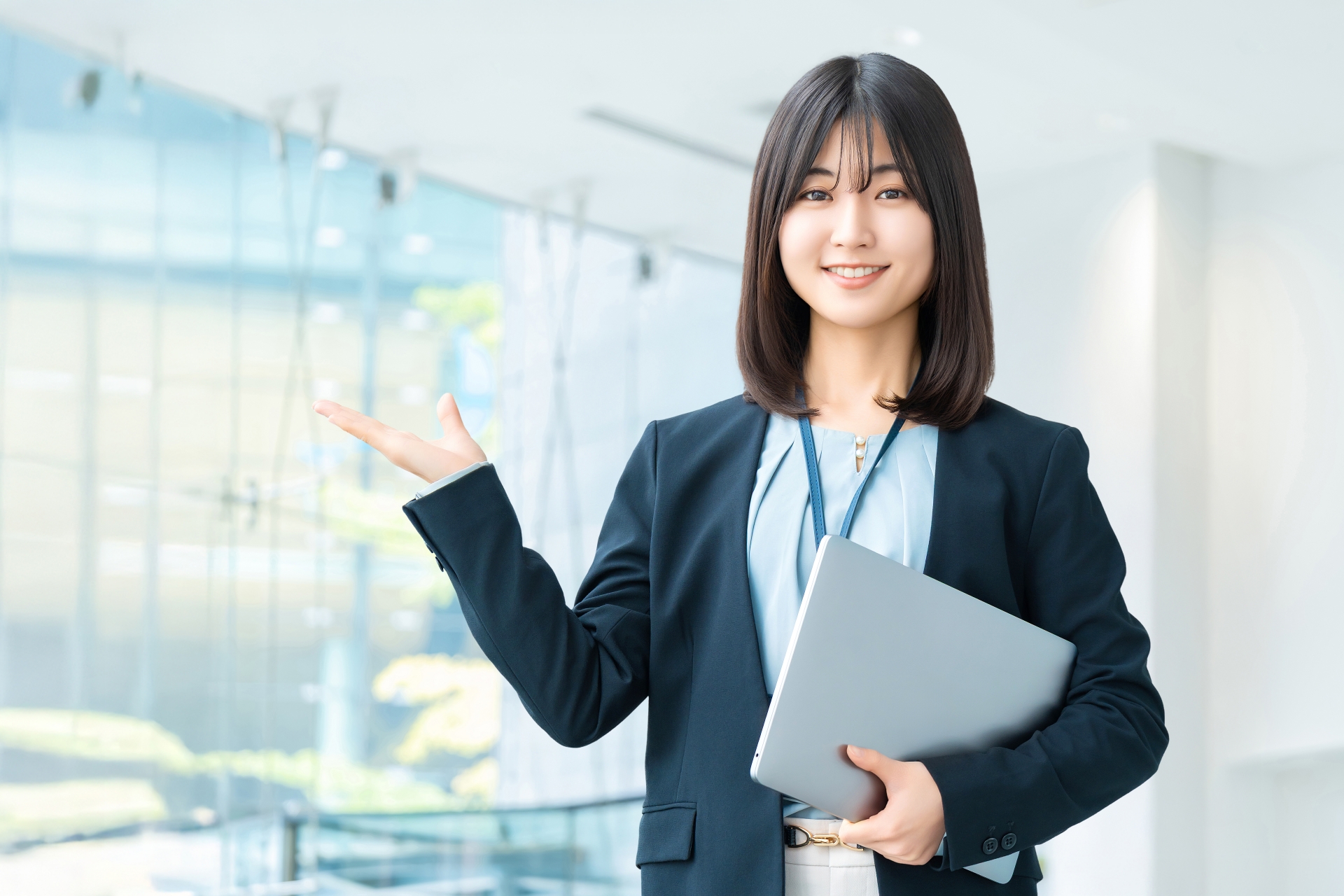 パソコンを持って案内をする笑顔の女性