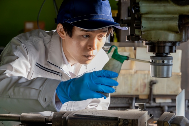 ボール盤のメンテナンスをする若い男性