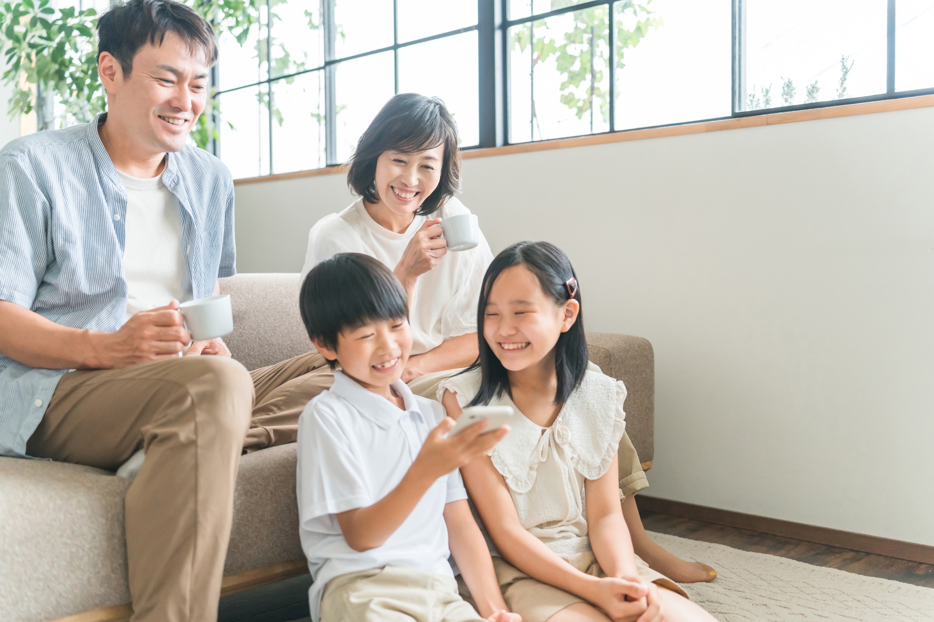 リビングでスマホを見る笑顔の家族