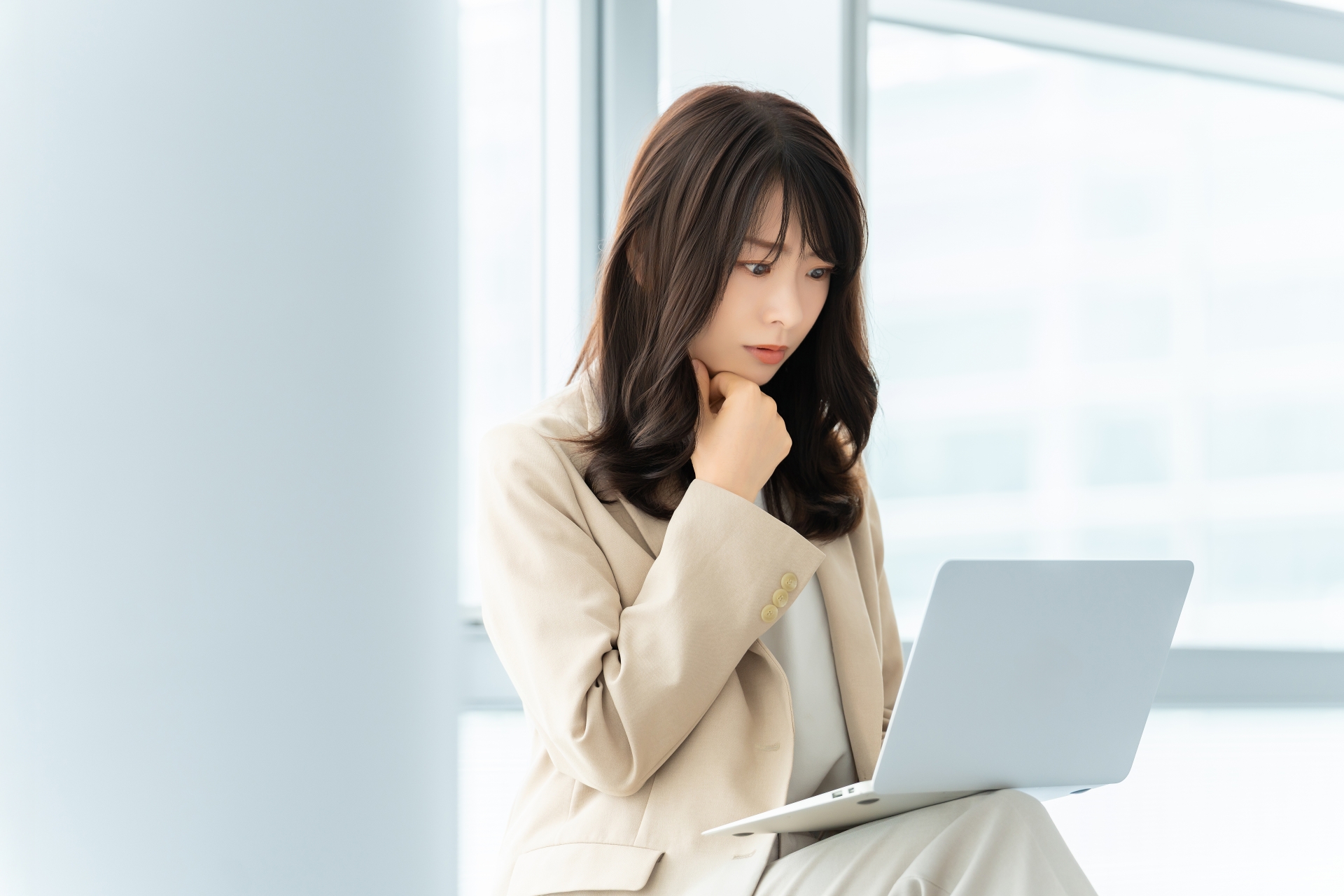 パソコンを使いながら考えごとをする女性