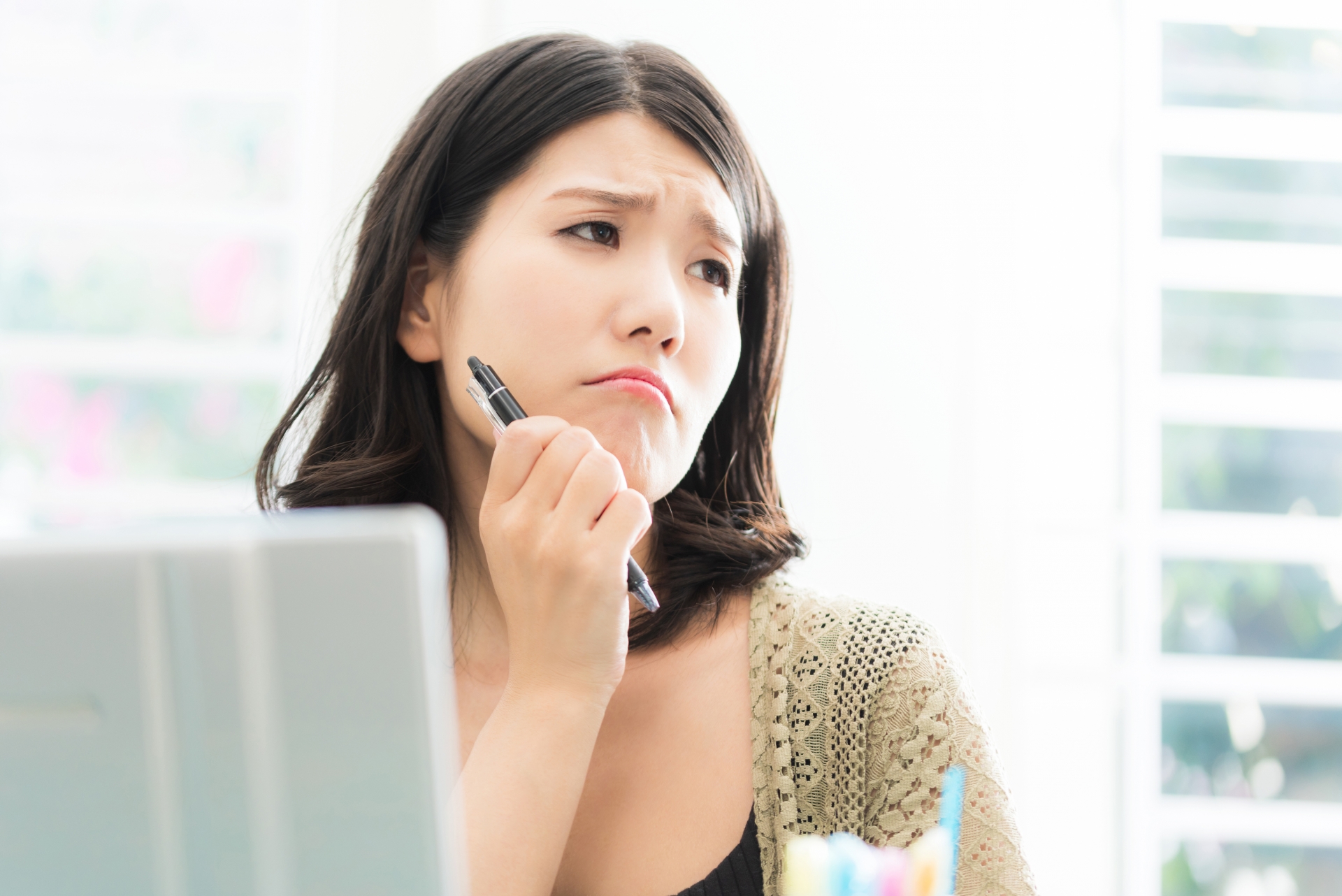 パソコンのある仕事場で悩む女性