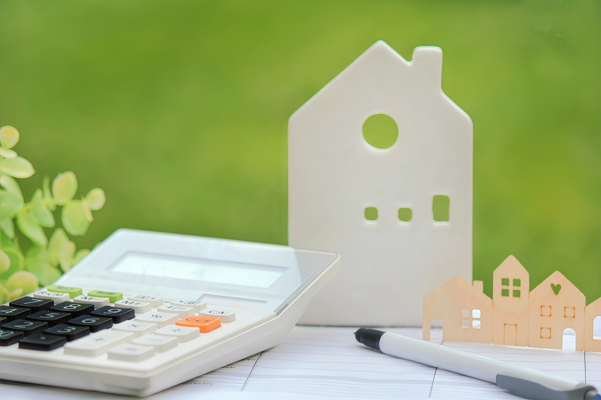 住宅の置物と電卓(グリーン背景)