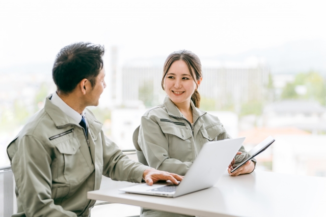 打ち合わせする作業着姿の建築士の男女