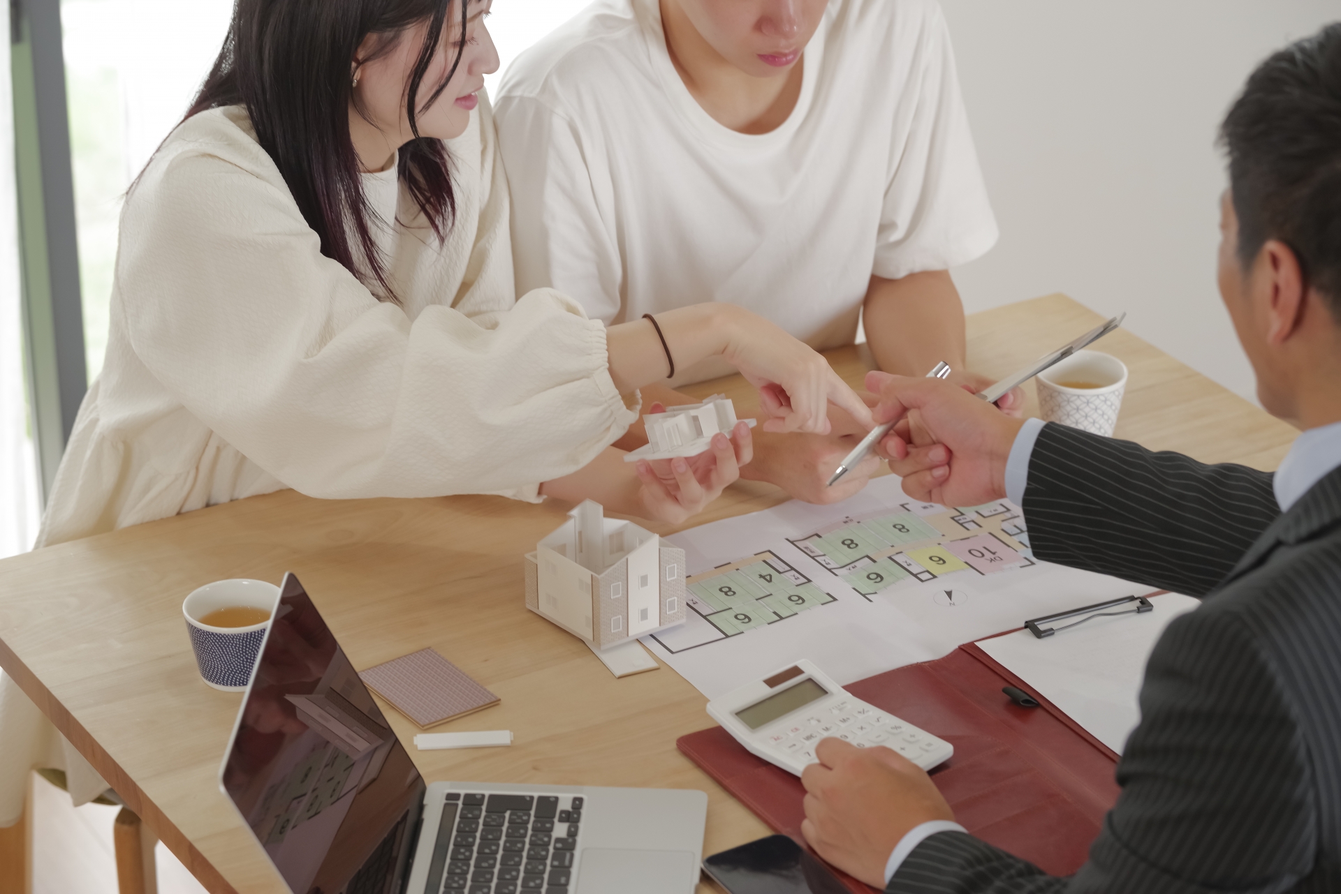 営業マンと家づくりの相談をする若い夫婦