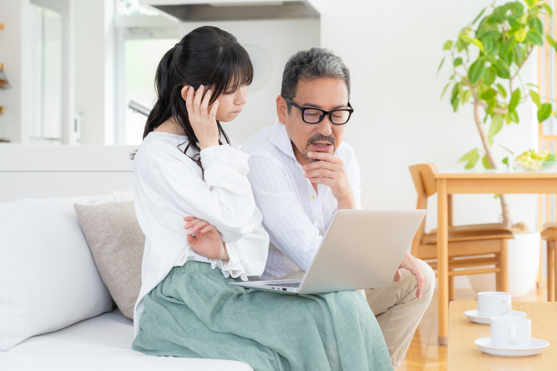 パソコンを見て悩む夫婦