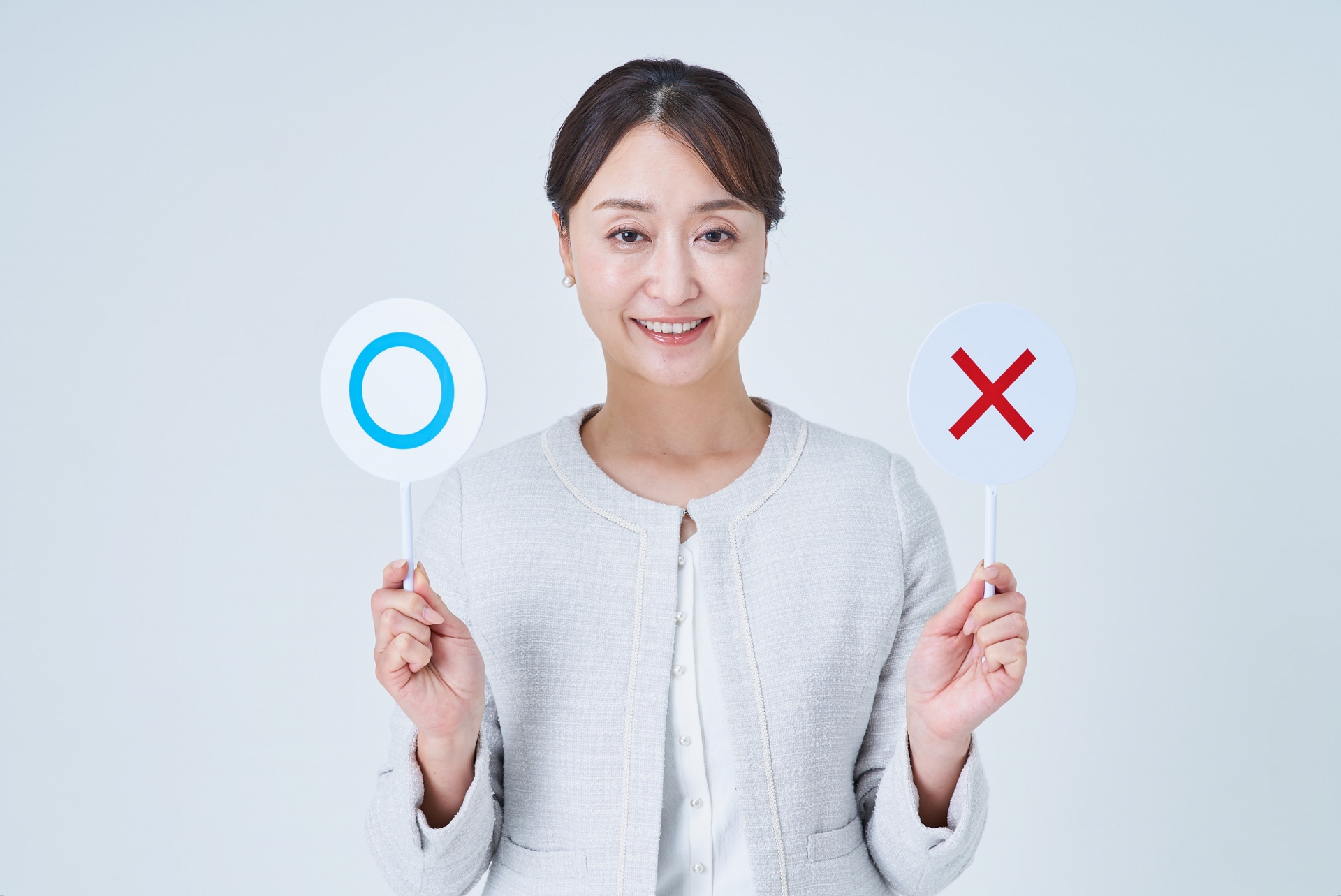 マルとバツのプレートを持つ女性