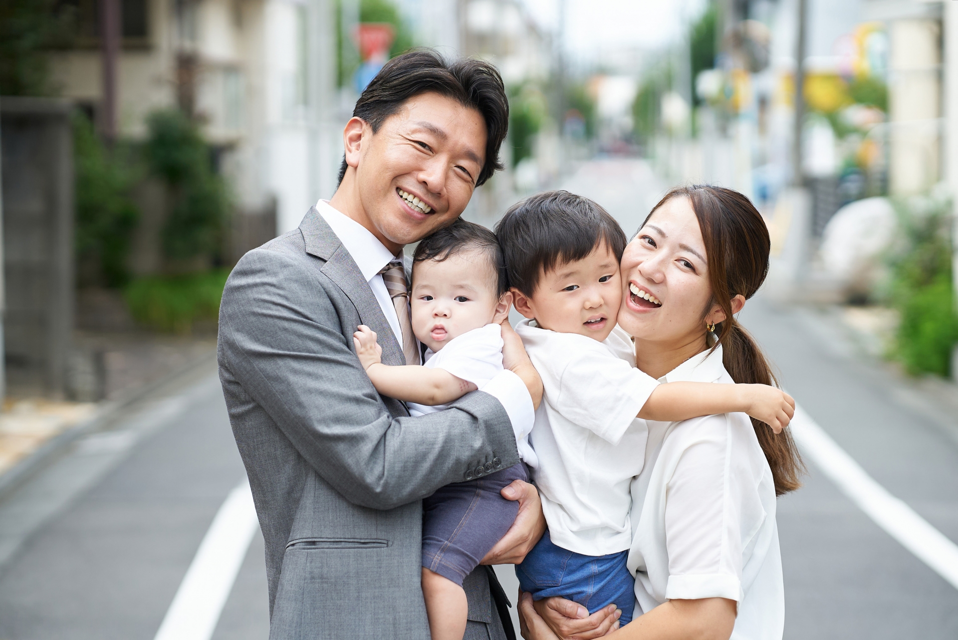 住宅街に立つ、笑顔の家族
