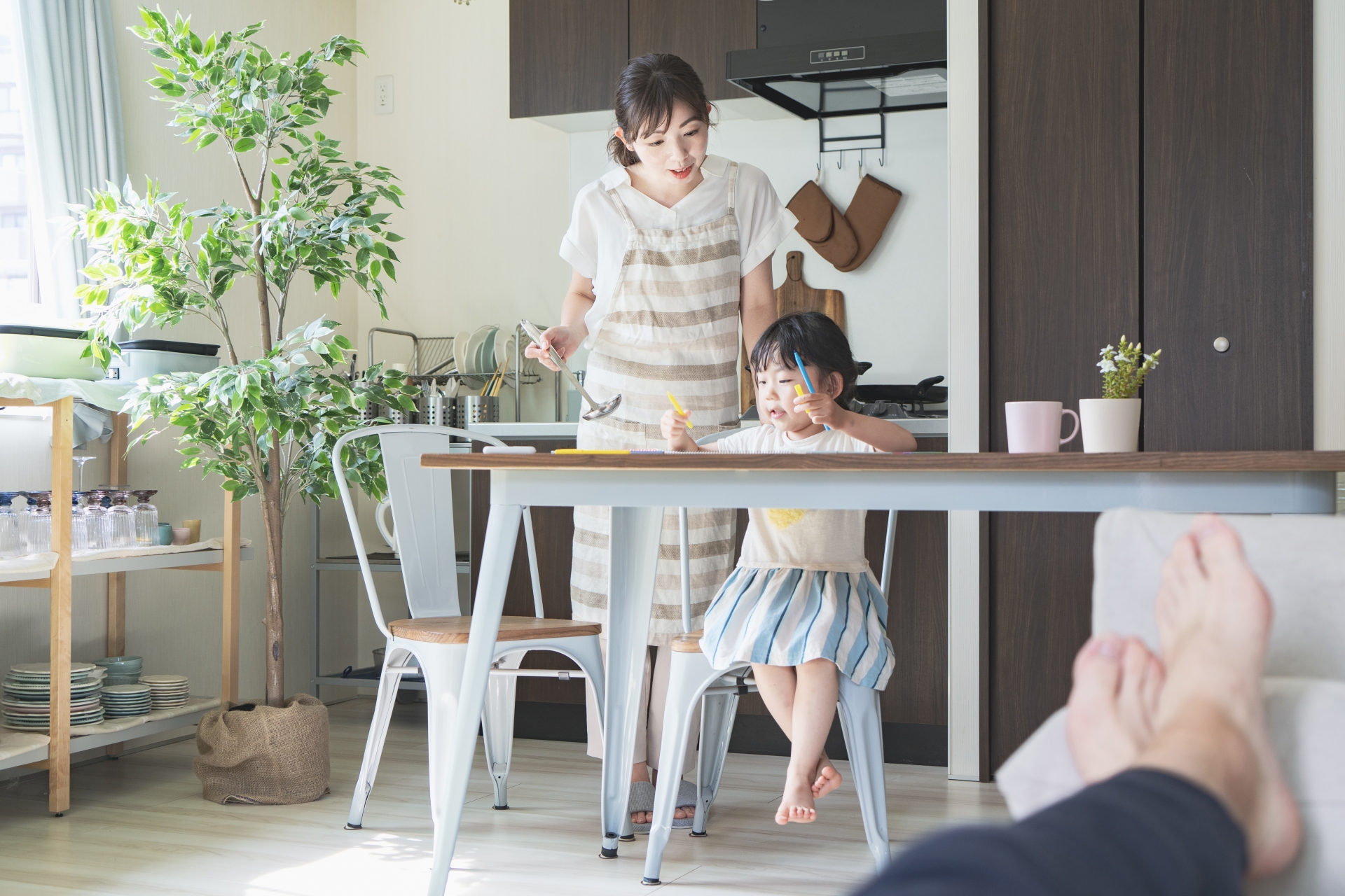 部屋でお絵かきをする女の子と見守る母親