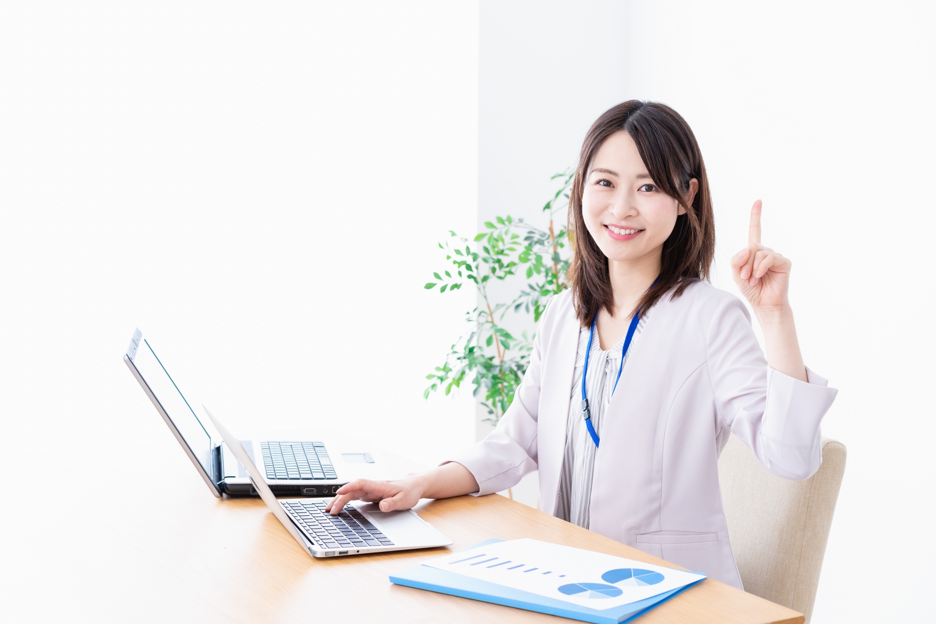 パソコンの前で指を立てた女性