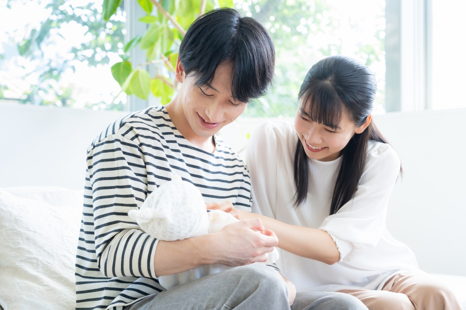 リビングで赤ちゃんを抱く若い家族