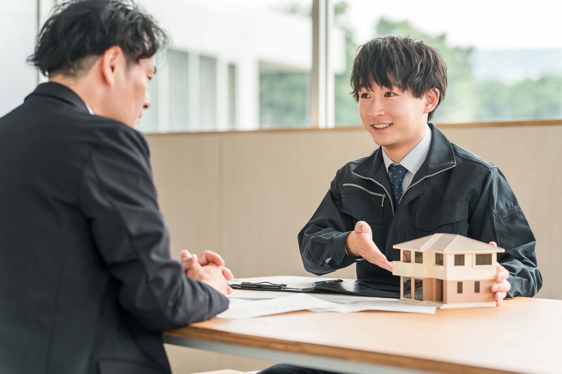 住宅模型を使って商談をするビジネスマン